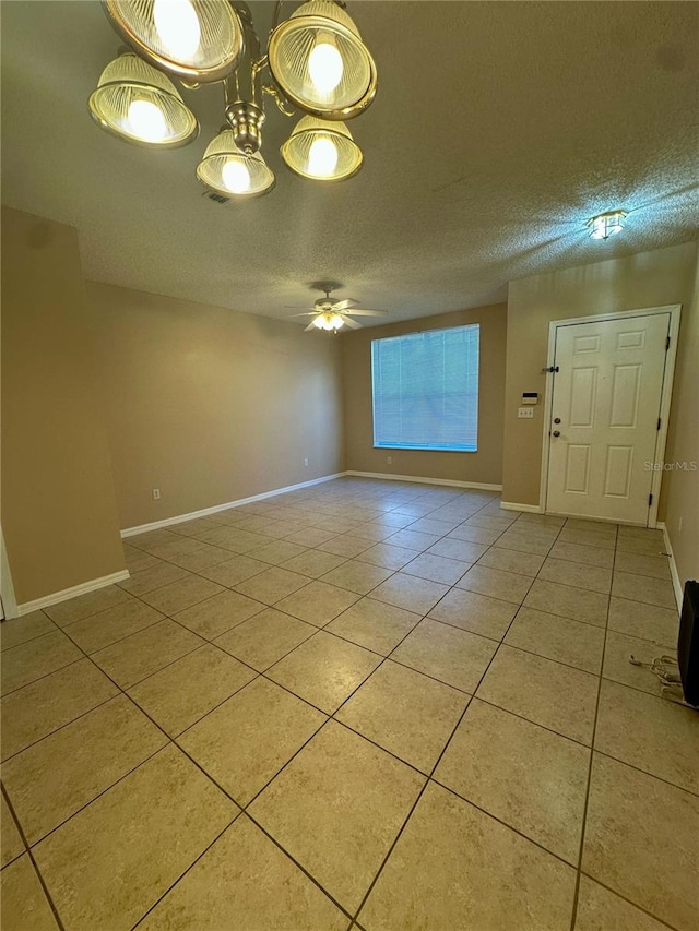 spare room featuring a textured ceiling, light tile patterned floors, baseboards, and ceiling fan