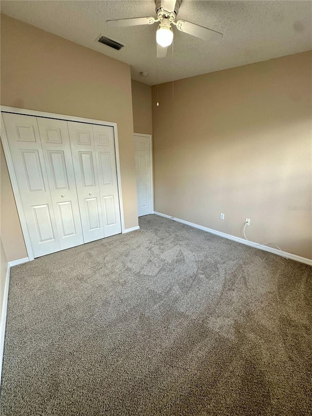 unfurnished bedroom featuring a closet, visible vents, a textured ceiling, and carpet floors