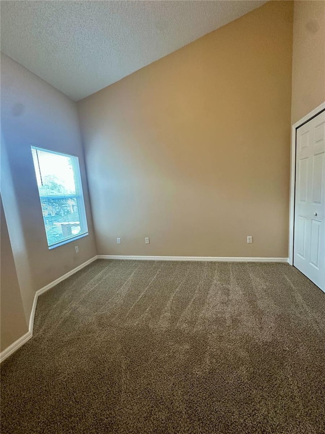 unfurnished room featuring baseboards, dark colored carpet, and a textured ceiling