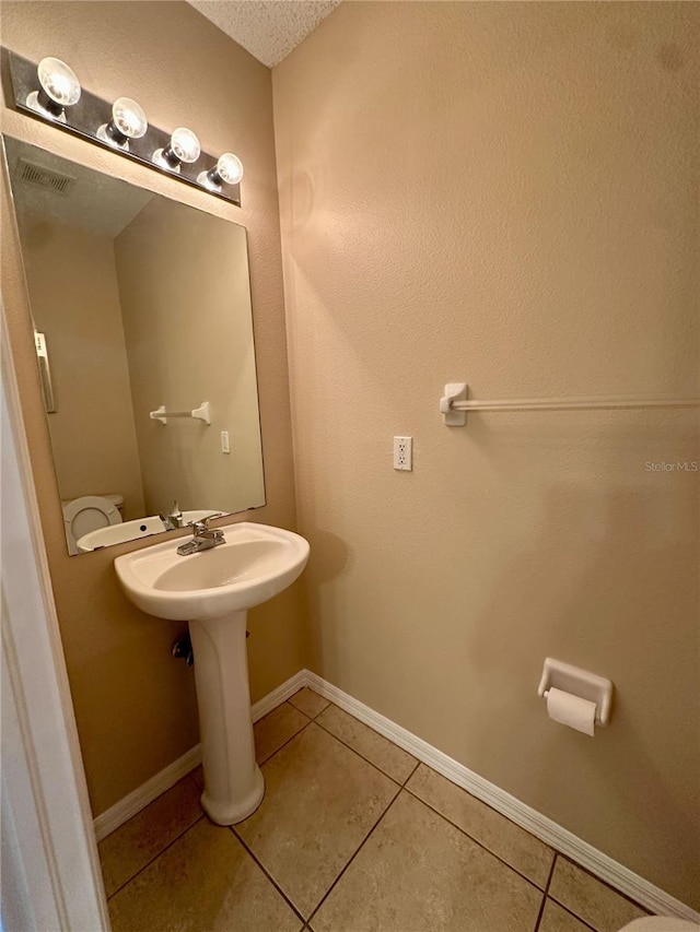 bathroom featuring tile patterned floors, visible vents, baseboards, and a textured ceiling