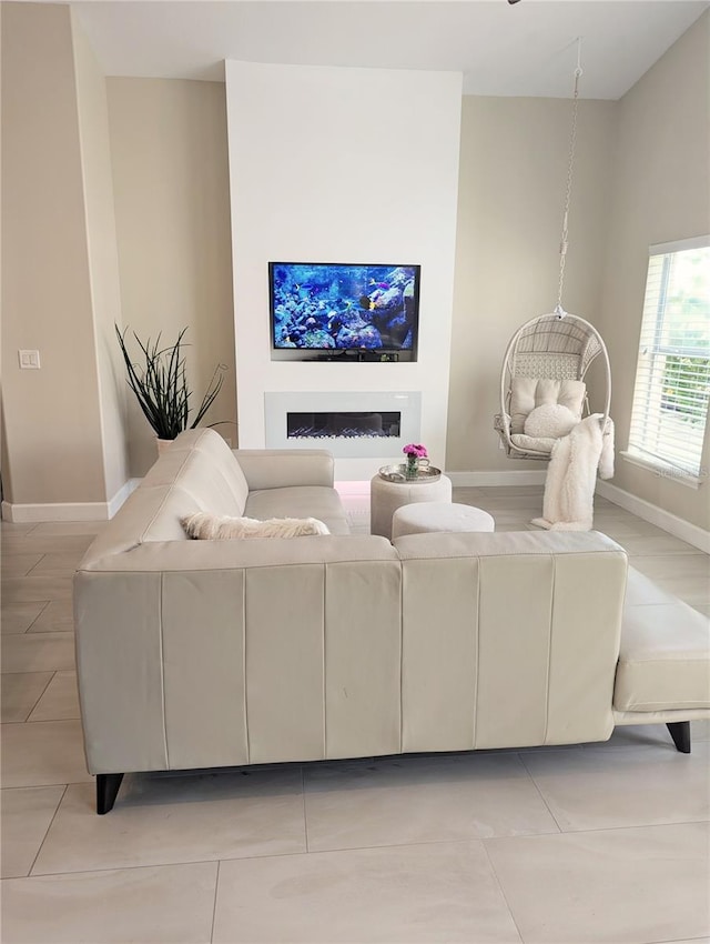 living room featuring light tile patterned floors, a fireplace, and baseboards