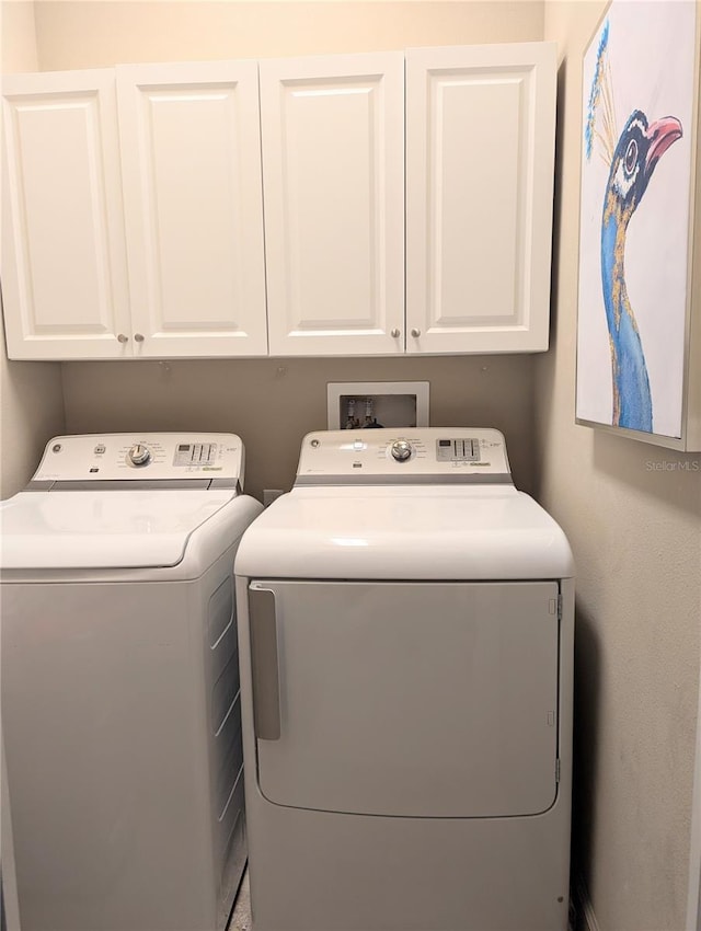 clothes washing area featuring cabinet space and separate washer and dryer