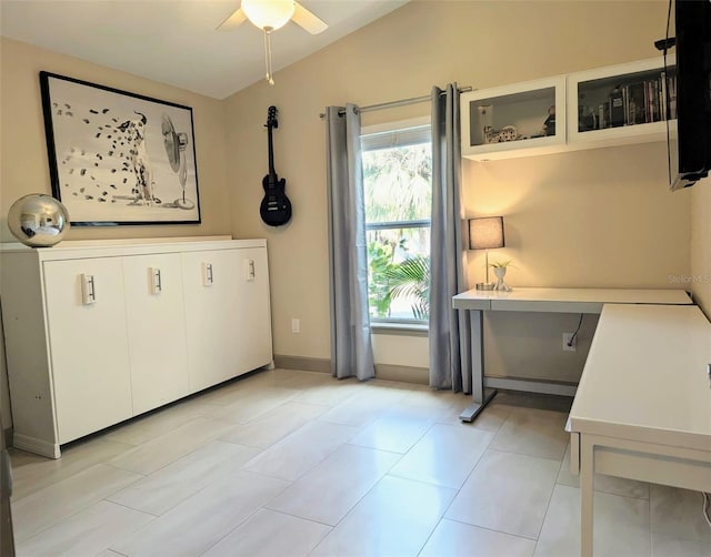 unfurnished office featuring vaulted ceiling, light tile patterned flooring, baseboards, and ceiling fan