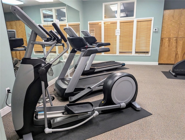 exercise room with baseboards and carpet floors