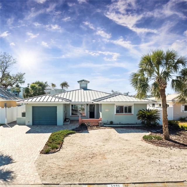 ranch-style house with a garage, decorative driveway, a standing seam roof, and fence