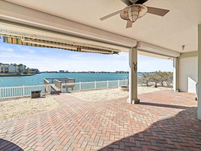 view of patio featuring fence, a ceiling fan, and a water view