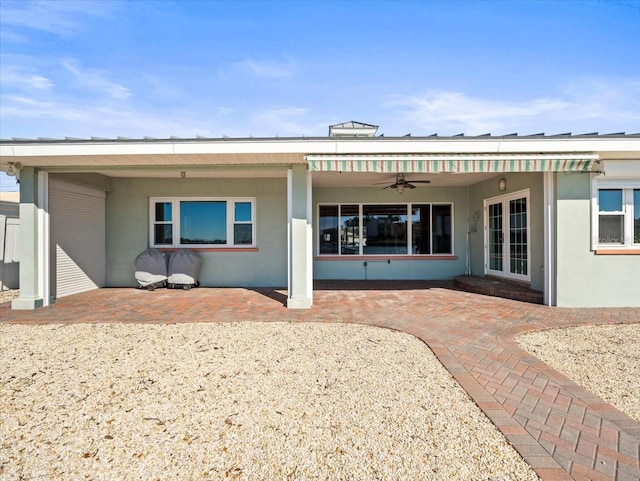 rear view of house featuring stucco siding, ceiling fan, and a patio area