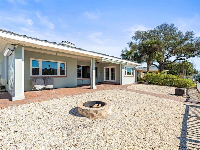 rear view of property featuring a patio area, french doors, an outdoor fire pit, and stucco siding