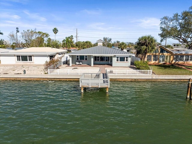 back of house featuring fence private yard, metal roof, a standing seam roof, and a water view