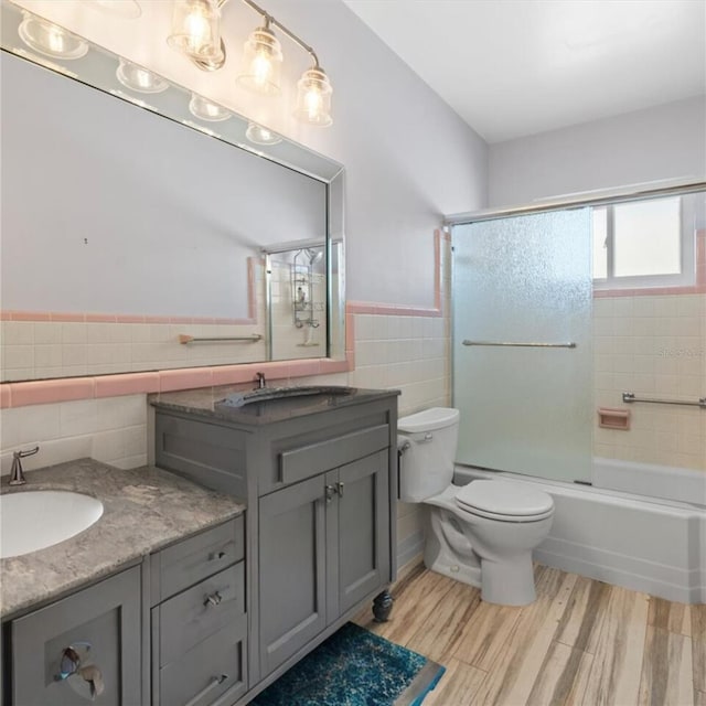 bathroom featuring toilet, wood finished floors, tile walls, wainscoting, and vanity