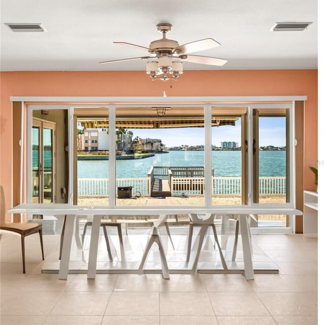 interior space featuring light tile patterned floors, visible vents, and a water view