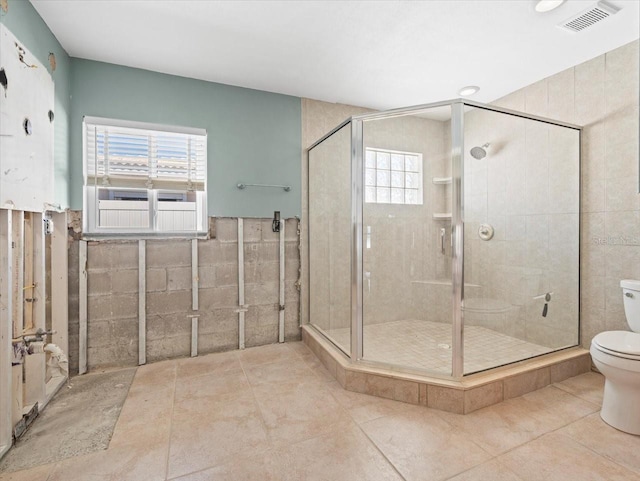 bathroom with visible vents, toilet, tile walls, and a stall shower