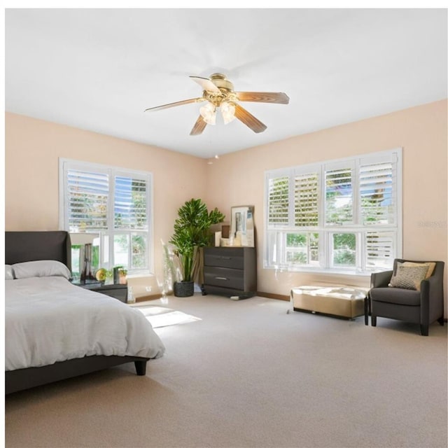 carpeted bedroom featuring baseboards, ceiling fan, and multiple windows