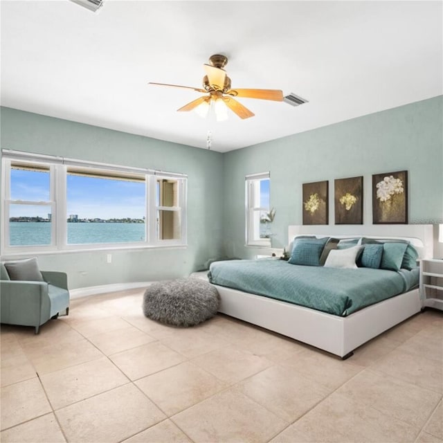 bedroom featuring a water view, a ceiling fan, light tile patterned flooring, and visible vents