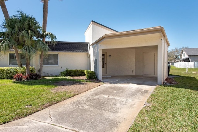 view of front of property featuring an attached carport, a front yard, roof with shingles, stucco siding, and driveway