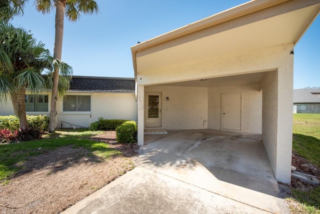 view of front of house featuring a carport, stucco siding, concrete driveway, and a shingled roof