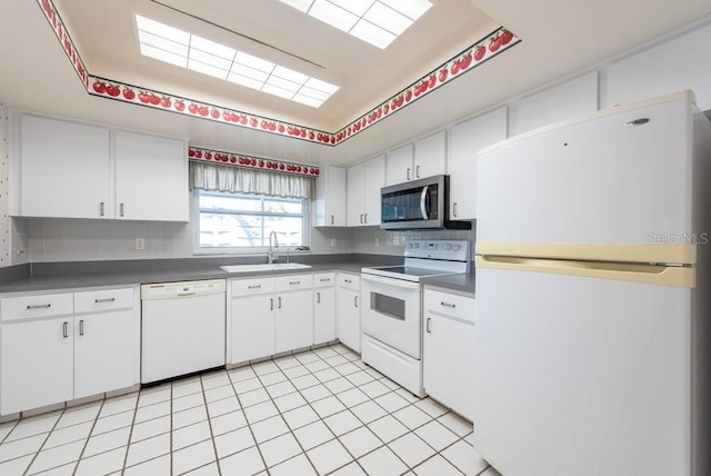 kitchen with white appliances, a sink, decorative backsplash, white cabinetry, and dark countertops