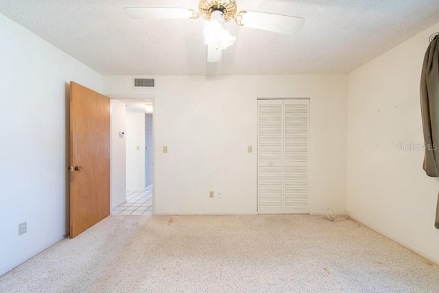 unfurnished bedroom with visible vents, a textured ceiling, a closet, and carpet flooring