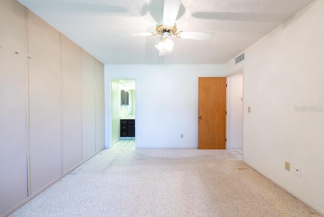 carpeted empty room featuring visible vents, a textured ceiling, and a ceiling fan