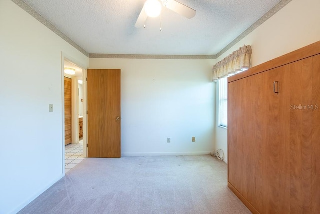 unfurnished bedroom featuring a textured ceiling, ceiling fan, baseboards, and light carpet