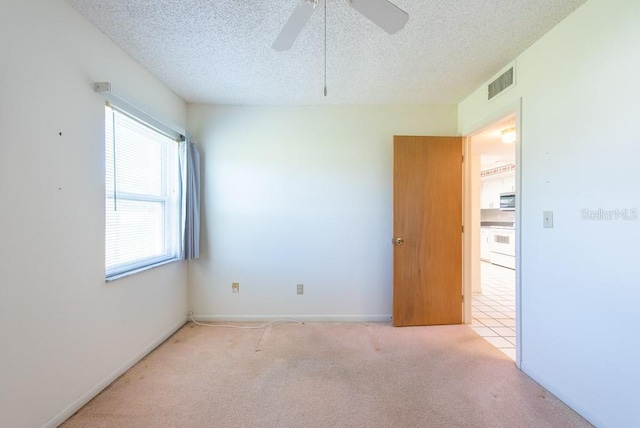 spare room with ceiling fan, visible vents, carpet floors, and a textured ceiling