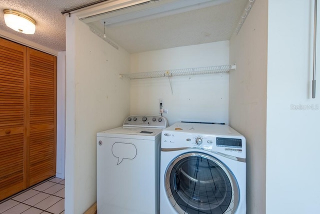 laundry room with washer and clothes dryer, laundry area, a textured ceiling, and light tile patterned floors