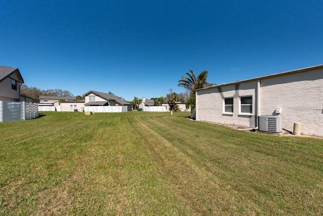 view of yard with central AC and fence