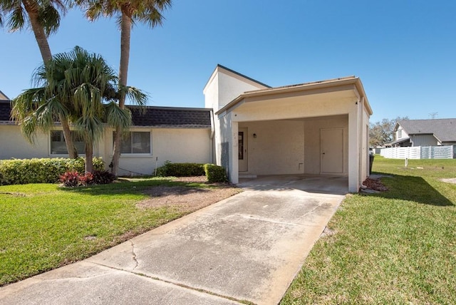 view of front facade featuring stucco siding, concrete driveway, a front lawn, and an attached carport