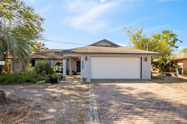 ranch-style house with decorative driveway, a shingled roof, an attached garage, and stucco siding