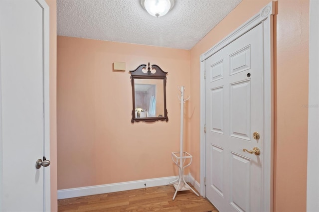 foyer with baseboards, light wood-style floors, and a textured ceiling