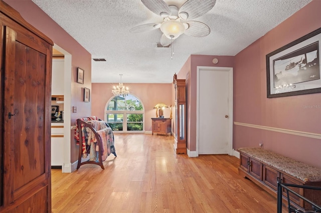 corridor featuring baseboards, visible vents, an inviting chandelier, a textured ceiling, and light wood-type flooring