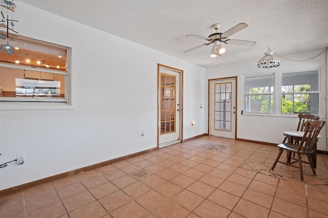 unfurnished room with ceiling fan, baseboards, a textured ceiling, and light tile patterned flooring