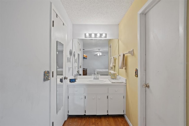 bathroom featuring ceiling fan, vanity, wood finished floors, ensuite bath, and a textured ceiling