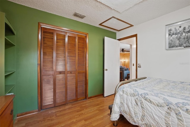 bedroom featuring visible vents, a textured ceiling, a closet, and light wood-style flooring