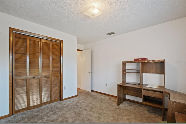 unfurnished bedroom with baseboards, visible vents, a closet, a textured ceiling, and carpet flooring