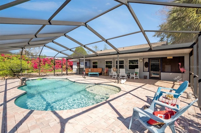 pool featuring outdoor lounge area, glass enclosure, and a patio area