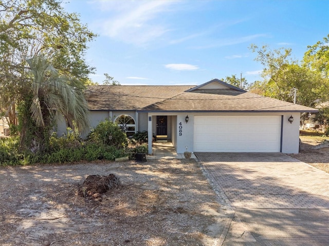 ranch-style home featuring a shingled roof, decorative driveway, a garage, and stucco siding