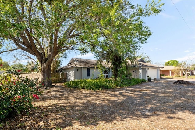 view of front of house with an attached garage, fence, driveway, and stucco siding