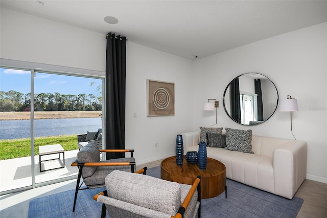 living area featuring baseboards and a water view