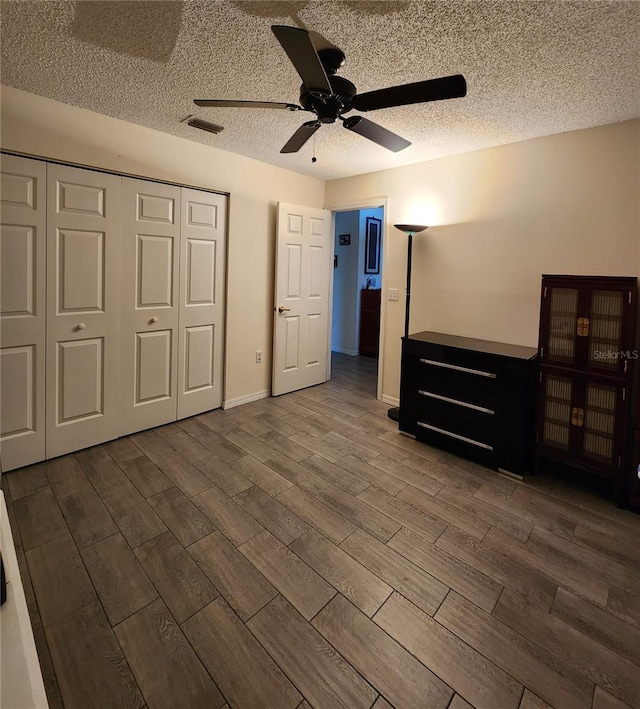 unfurnished bedroom with visible vents, a textured ceiling, wood finished floors, a closet, and ceiling fan