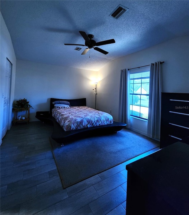 bedroom with visible vents, a textured ceiling, ceiling fan, and wood finished floors