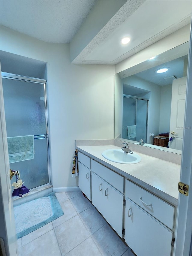 bathroom featuring tile patterned flooring, a shower stall, vanity, and baseboards