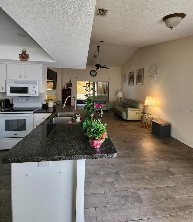 kitchen featuring visible vents, a peninsula, white cabinets, white appliances, and a sink