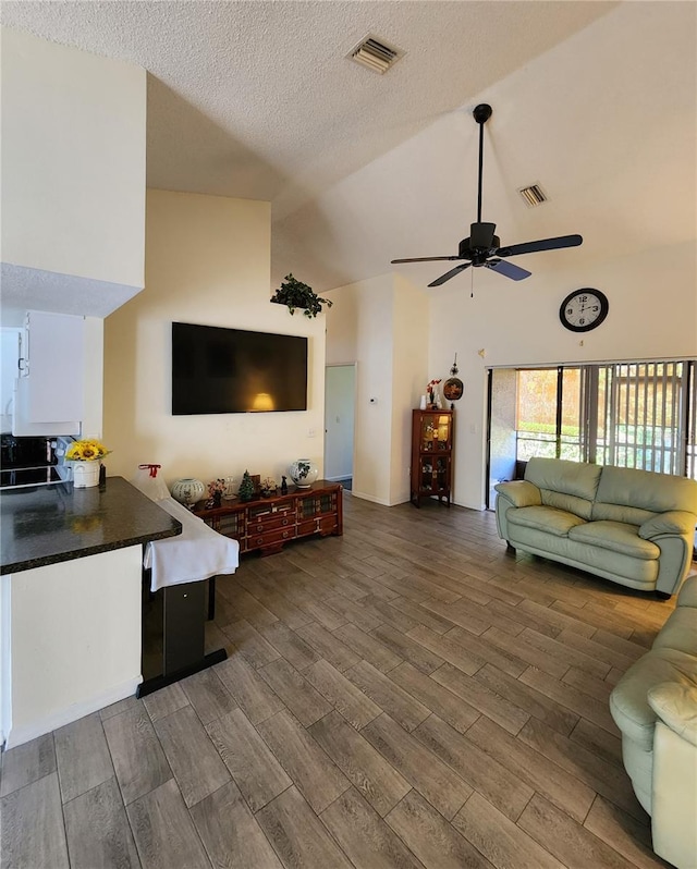 living area with visible vents, a textured ceiling, wood finished floors, and a ceiling fan