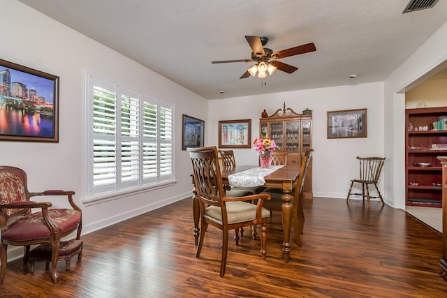 dining space with a ceiling fan, visible vents, dark wood-style flooring, and baseboards