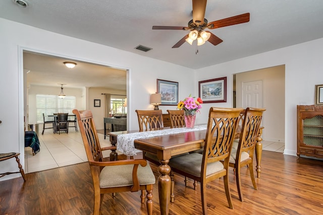 dining space featuring visible vents, a ceiling fan, and wood finished floors