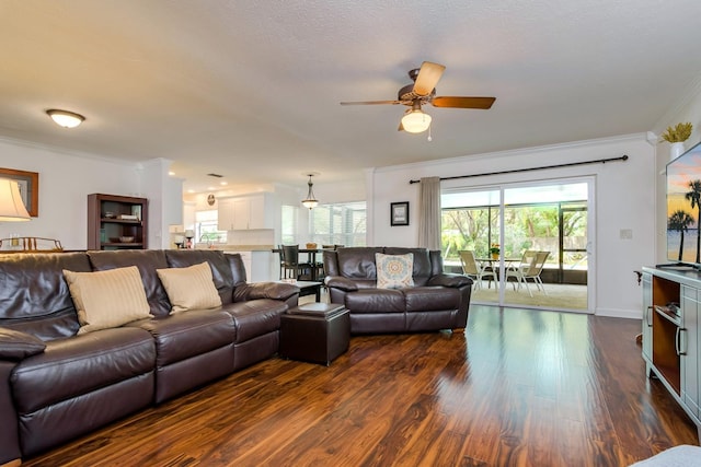 living room featuring dark wood finished floors, baseboards, crown molding, and a ceiling fan