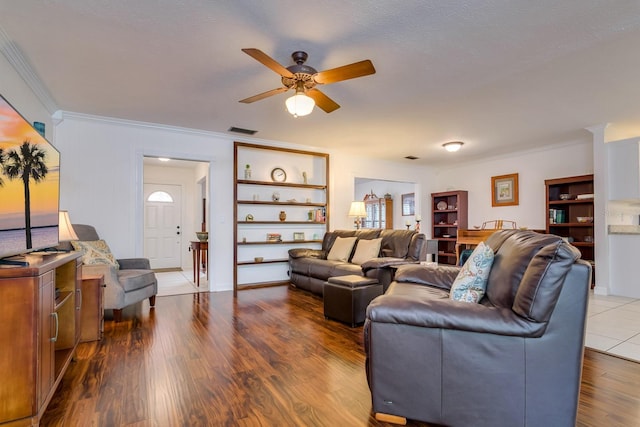 living room featuring visible vents, crown molding, ceiling fan, and wood finished floors