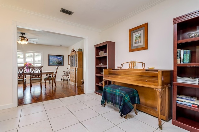 tiled office space featuring visible vents, baseboards, crown molding, and a ceiling fan