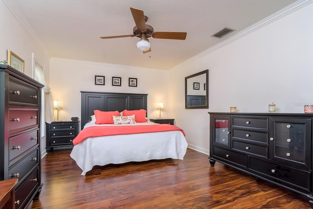 bedroom featuring baseboards, wood finished floors, visible vents, and ornamental molding